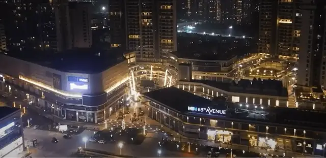 M3M 65th Avenue – retail blocks and signage lit up at night (photograph)