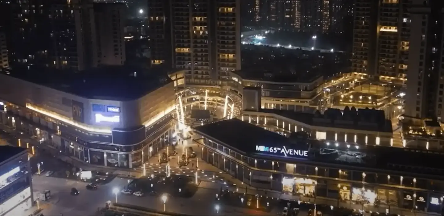 M3M 65th Avenue – retail blocks and signage lit up at night (photograph)