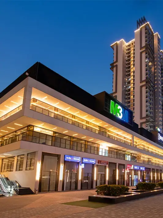 M3M Corner Walk – retail frontage lit up at dusk