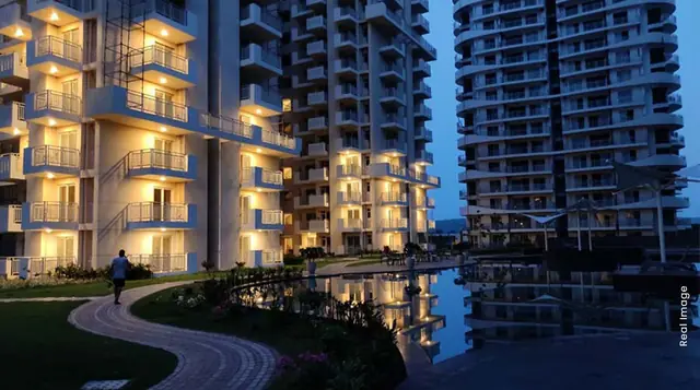 M3M Ikonic – towers lit up at night beside the water feature (actual photograph)